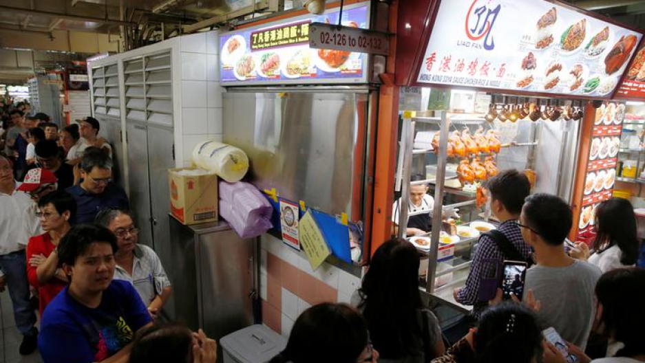 People queue outside hawker Chan Hong Meng's Michelin star awarded stall, for his soya sauce chicken rice and noodle at a food market in Singapore